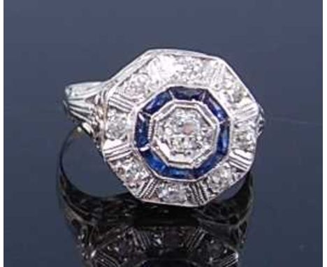 A white metal, diamond and sapphire Art Deco style circular cluster ring, comprising a centre bezel set Old European cut diam