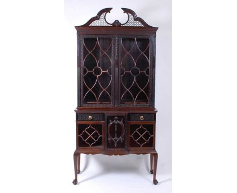 An Edwardian mahogany Chippendale Revival cabinet on stand, having a pierced swan-neck pediment and blind carved frieze over 