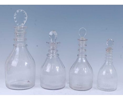 * A matched set of four graduated late Georgian lead glass decanters, the lozenge stoppers above a triple ring neck, flat cut