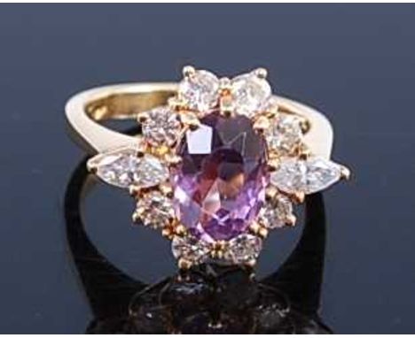 A yellow metal, amethyst and diamond oval cluster ring, featuring an oval faceted amethyst within a border of eight round bri