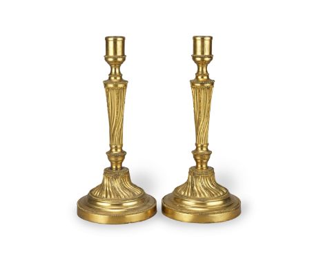 A pair of Louis XVI style gilt-brass candlesticksLate 19th centuryThe plain nozzles above spiral cast tapering vase supports,