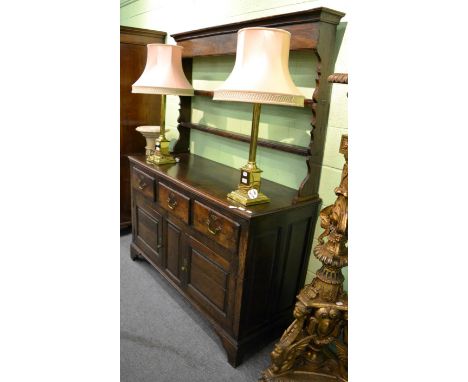 An 18th century oak enclosed dresser and rack, with two shelves and shaped end supports, the base with three deep drawers abo