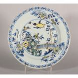 An 18th century London delft polychrome plate with bird, root and fence decoration, 9" dia (