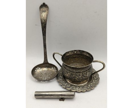 A Victorian silver strainer spoon, 48.1g together with an Indian white metal twin handled cup and saucer 74.8g and a white me