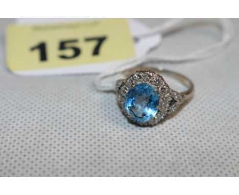 An aquamarine and diamond cluster ring with three diamonds to each shoulder, the centre stone 10mm high. In white gold marked