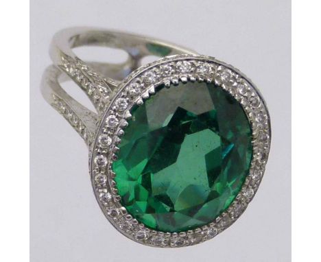 Green stone and diamond oval cluster ring, the white gold shank set  with melee diamonds, ring size M