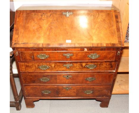 An early 18th Century walnut and herringbone banded bureau with sloping flap enclosing stepped interior and well, four gradua