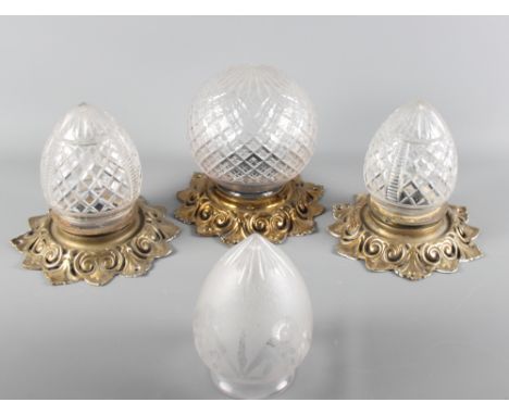 A pair of ovoid cut glass ceiling light shades with gilt metal mounts, another spherical diamond cut shade with matching moun