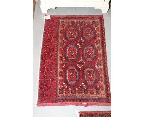 A Bokhara rug decorated six octagonal guls with a candlestick on a red ground with a candlestick design border, 44" x 30" app