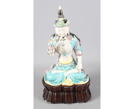 A Chinese Republic period porcelain Buddha holding a pomegranate decorated in polychrome enamel (damages and losses), on carv