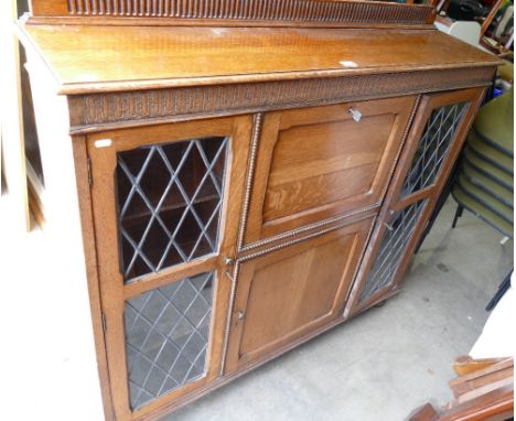 20th Century oak side cabinet with drop down writing top between leaded glazed door on bun feet (key to be collected from the