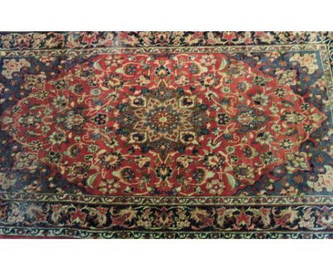 A Tabriz burgundy ground small carpet woven with a floral design within a wide border, 280 x 160 cm