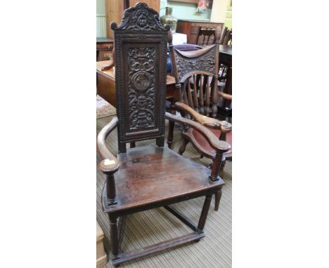 A late 19th century oak open armchair, having panel back with Green Man carved crest & a profile Elizabethan Gentleman, raise