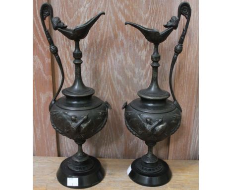 A pair of Continental cast metal ewer garnitures, in the form of Classical decoration raised on black slate bases, 35.5cm, hi