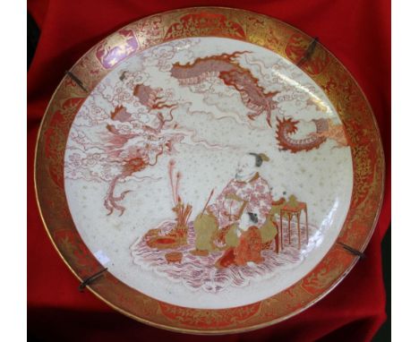 A Japanese Satsuma ceramic charger, hand painted and gilded decoration, a seated scholar with children observe a dragon, pain