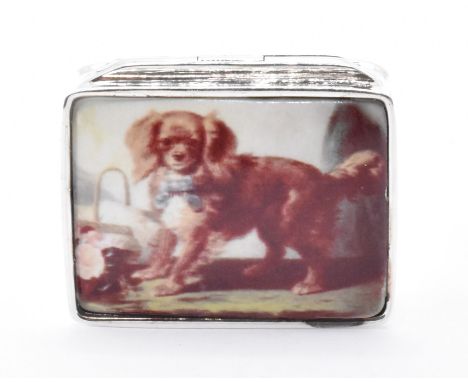 A silver and enamel lidded pill pot. The pot having an enamel panel to the lid depicting a spaniel dog. Measures 3cm x 2cm x 