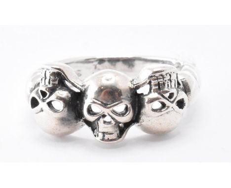 A silver ring having three moulded skulls to the head with pierced eyes. Marked 925. Weight 4.7g. Size P.&nbsp;