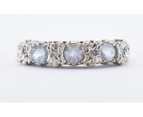 A hallmarked 9ct gold three stone ring. The ring being set with three round cut pale blue stones in illusion settings with di