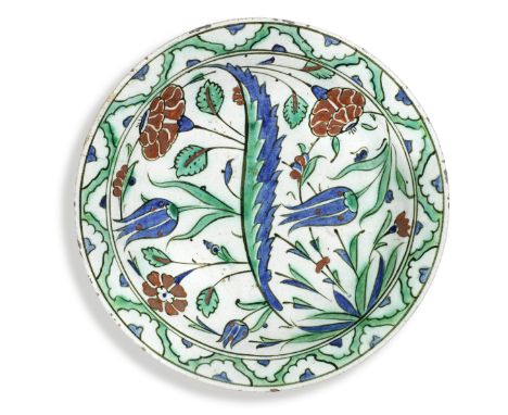An Iznik pottery dish Turkey, late 16th Centuryof shallow rounded form with slightly everted rim, decorated in raised-red, co
