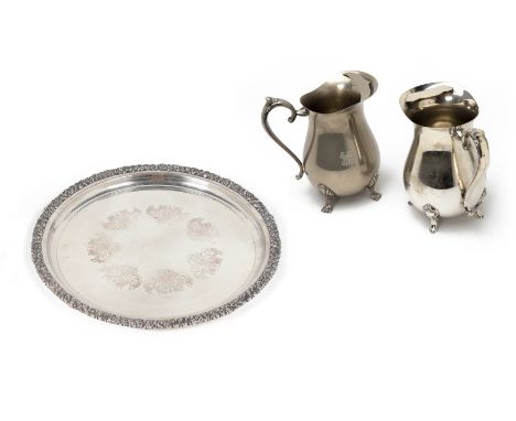 TWO WATER PITCHERS AND A CIRCULAR TRAY
The silver plated tray by Hecworth, with elaborate foliate border; a silver plated wat