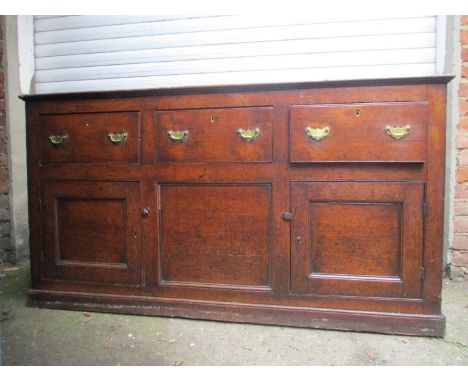 A George II oak dresser with three in-line drawers and a central panel, flanked by a pair of panelled doors, on a plinth 35"h