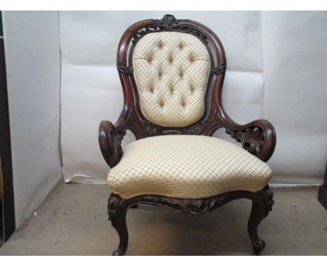 A Victorian walnut nursing chair with a pierced, scrolled leaf carved back and arms, part button upholstered in a cream fabri