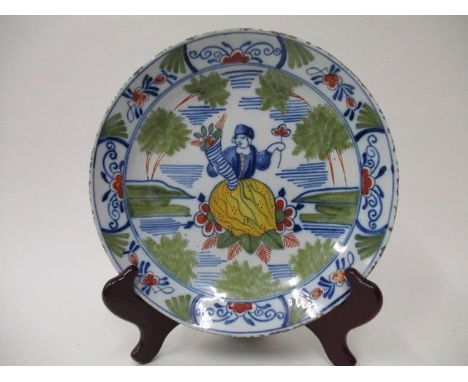 An early 19th century Dutch Delft dish decorated in polychrome enamels with a woman and a blue P K mark 9 1/4" dia. 