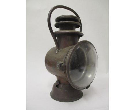 An early 1900s Dietz brass automobile car lamp with a carrying handle, clear lense to the front and a red panel to the revers