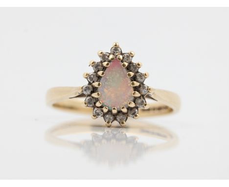 A hallmarked 9ct yellow gold opal and diamond cluster ring, set with a pear cut opal cabochon, surrounded by single-cut diamo