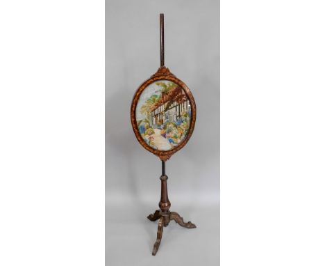 A Victorian mahogany pole screen, circa 1870, with foliate decoration and stringing, the oval banner with a later tapestry pa