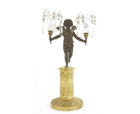 A Regency twin-branch gilt bronze candelabra,modelled as a putto holding aloft two glass candle sconces, with prismatic drops