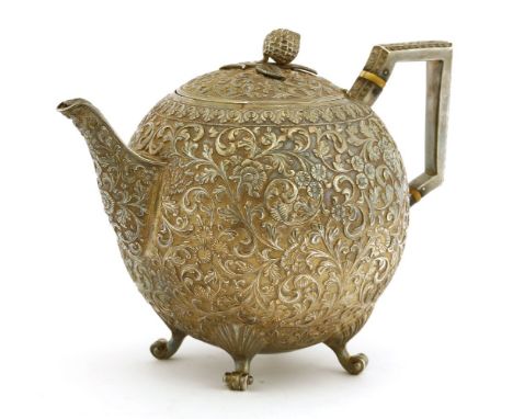 An Indian silver repoussé teapot, by Oomersi Mawji and Sons, Kutch, 1860-1930, the cover with flower head knop over the globu