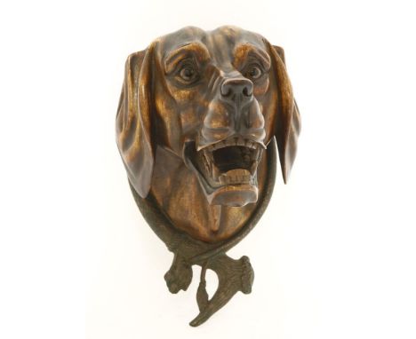 A carved wooden dog's head wall mask,late 19th century, well modelled with his jaws open and glass eyes, within a cast bronze