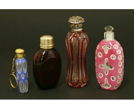 Four Victorian scent bottles,hallmarks indistinct,a faceted and flash-dipped waisted body below a silver cover,10cm,one with 