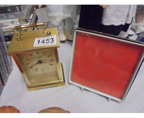 A brass carriage clock and a Rolls Royce plaque.