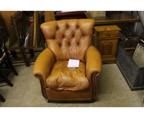 A brown leather button back armchair 