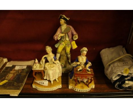 A continental porcelain figure in the form of an 18th Century style figure playing tennis, together with two figurines 