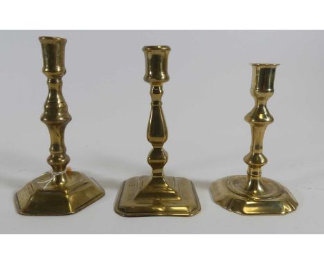 An early 18th century brass candlestick having a knopped stem to hexagonal foot, height 18cm, together with two others
