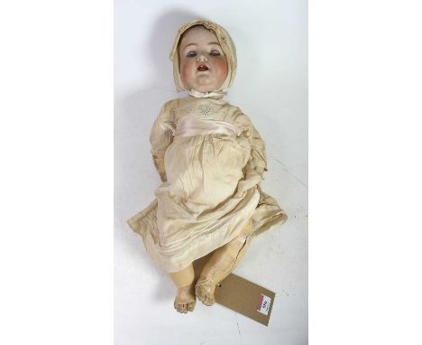 A vintage bisque headed doll, having rolling eyes and showing one upper tooth, the head impressed 126 to the reverse, length 
