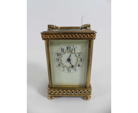 A lacquered brass carriage clock, having a visible platform escapement and white enamel dial showing Arabic markers and flora