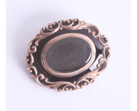 An early Victorian fancy scroll mourning brooch set with black enamel and gold scroll overlay, approx. 13.35g.