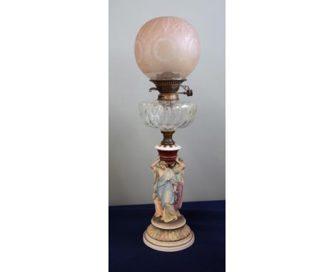 A Victorian oil lamp with glass reservoir and a smokey brown shade with a ceramic three lady base, height 67cm.