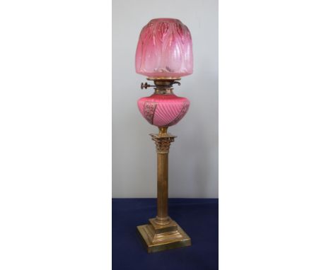 A Victorian oil lamp with a pink reservoir and a pink shade on a brass column base, height 74cm.