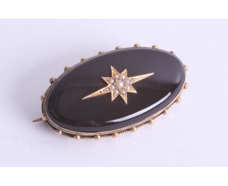 A large cabochon oval Onyx set with gold and seed pearl star, fitted with glass inset, stamped 15ct, approx. 12.40g.