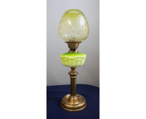 A Victorian oil lamp with a green glass column and a green glass shade decorated with flowers on a brass base, height 62cm.