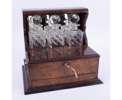 A Victorian mahogany and walnut three bottle tantalus with the front double hinged with lock and concealed drawer (opened by 
