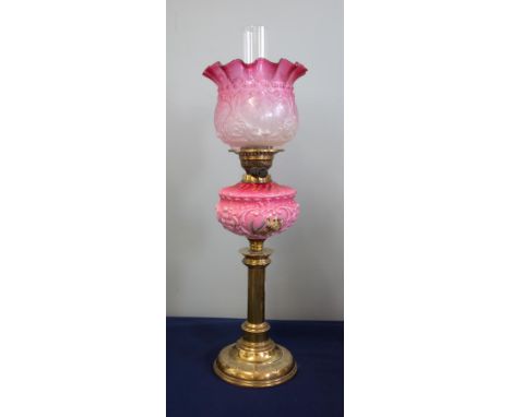 A Victorian oil lamp with pink glass column decorated with flowers and a pink shade on brass base, height excluding chimney 6