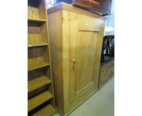 A 19th century continental pine robe enclosed by a rectangular moulded panelled door, the interior fitted with a hanging rail