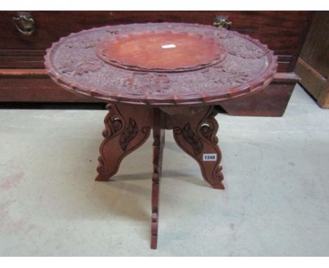 An Indian hardwood occasional table of circular form with shaped outline, profusely carved foliate elephant and further detai