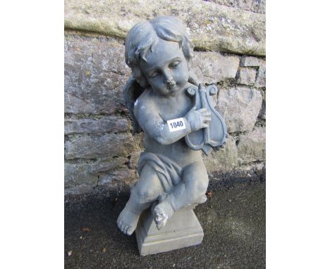 A composite, to simulate lead, garden ornament in the form of a winged cherub/putti, seated on a squat plinth playing a harp/